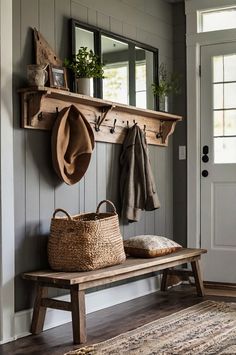 a wooden bench sitting under a mirror next to a coat rack with hats on it