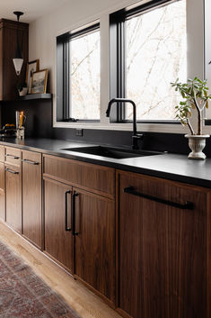 a kitchen with wooden cabinets and black counter tops, along with a rug on the floor