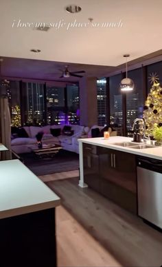 a kitchen with a christmas tree in the center and windows overlooking city lights at night