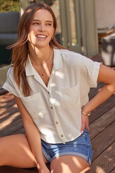 a woman is sitting on a wooden deck and posing for the camera with her hands on her hips