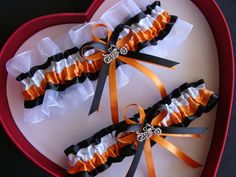 two orange and black garters in a heart shaped box with ribbon tied around them