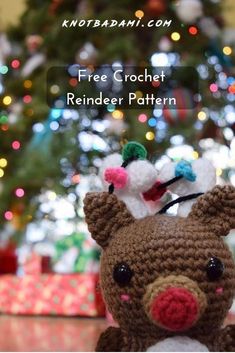 a crocheted reindeer is sitting in front of a christmas tree with the words free crochet reindeer pattern on it