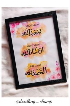 an arabic calligraphy is displayed in a black frame on a white sheet with pink and yellow flowers