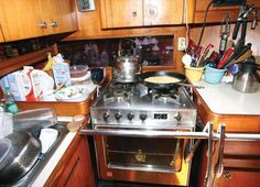 a stove top oven sitting inside of a kitchen next to a counter with pots and pans on it