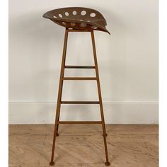 a wooden stool sitting on top of a hard wood floor next to a white wall