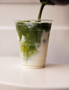 a cup filled with green liquid sitting on top of a white counter