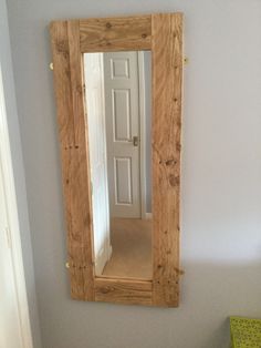 a wooden mirror hanging on the wall above a bed in a room with white walls