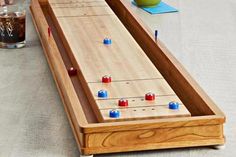 two people playing shuffle board game on the table next to a cup and glass with soda in it