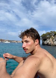 a shirtless man sitting on the bow of a boat