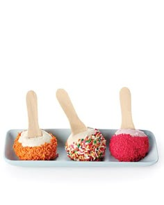 three desserts with wooden spoons on a blue tray, one is covered in sprinkles and the other has white icing