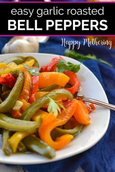 a white plate topped with bell peppers next to garlic and green beans on a blue table cloth