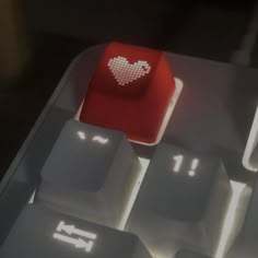 a computer keyboard with a red heart on it's key board and light shining through the keys