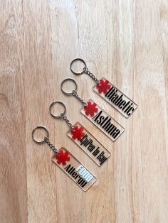 three metal key chains with red crosses and the words medical asthma written on them are laying on a wooden surface