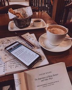 an open book sitting on top of a table next to a cup of coffee