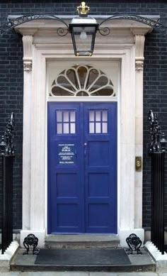 a blue door is in front of a brick building with wrought iron railings on either side