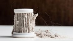 a close up of a cup on a table with some stuff in it and one piece of yarn next to it