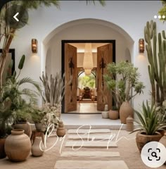 the entrance to a house with potted plants and cactuses on the ground in front of it