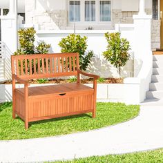 a wooden bench sitting on top of a lush green field next to a white house