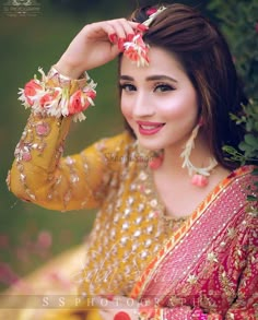 a beautiful woman in a yellow and red outfit with flowers on her hair posing for the camera