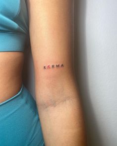 a woman's arm with the word karma tattooed on her left side ribcage