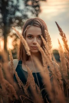 a woman standing in tall grass looking at the camera