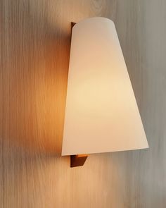 a lamp that is on the wall next to a wood paneled wall with a white shade