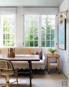 a living room filled with furniture and lots of windows covered in white shuttered curtains