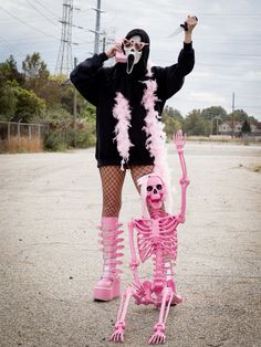 a woman in pink and black is standing next to a skeleton with her hands up