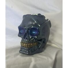 a black skull with blue eyes and gold teeth