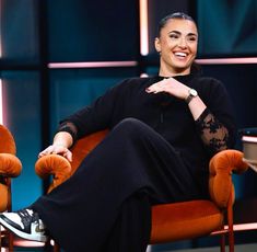 a woman sitting in an orange chair smiling