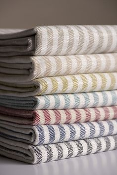 a stack of folded towels sitting on top of a white tablecloth covered in multicolored patterns