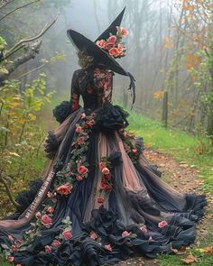 a woman in a long black dress with flowers on her head is standing in the woods