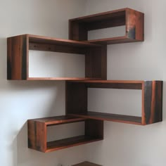 three wooden shelves on the wall with one shelf open to show books and other items