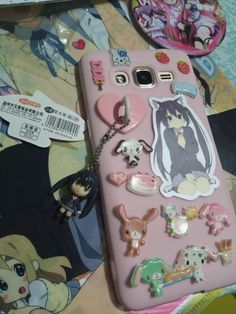 a pink cell phone with many different stickers on it's back cover and keychain