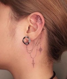 a woman's ear with tattoos on it and a chain hanging from the side