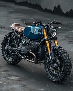 a blue and black motorcycle parked on top of a parking lot next to a cement wall