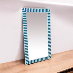 a mirror sitting on top of a wooden table next to a shelf with a vase