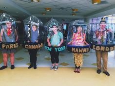 four people standing in front of three fake glass cases with faces on them and words that say paris, new york, london