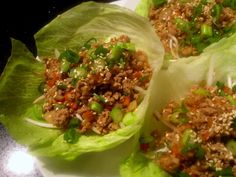 three lettuce wraps filled with meat and veggies on a white plate