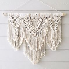 a macrame hanging on a window sill in front of a white wall