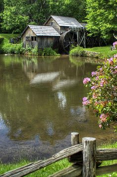 an old mill sits on the edge of a pond