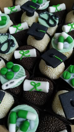 graduation cupcakes are decorated with green and white icing, black caps, and scissors