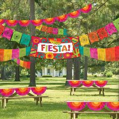 a park filled with lots of benches covered in colorful blankets and banners that read fiesta