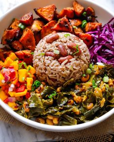 a white bowl filled with rice, vegetables and other foods on top of a table