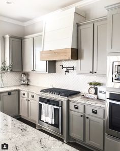 a kitchen with marble counter tops and gray cabinets