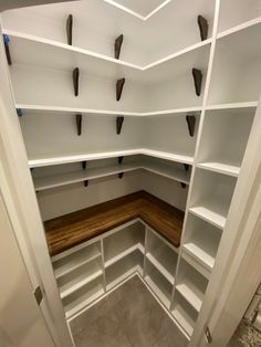 an empty room with white shelves and wooden flooring in the corner is seen from the doorway