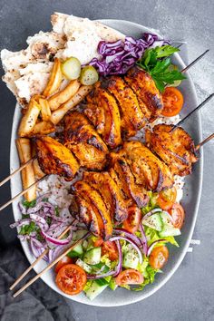 chicken kabobs with rice and vegetables on a plate