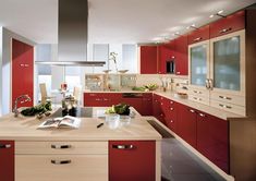 a modern kitchen with red cabinets and white counter tops, along with an island in the middle