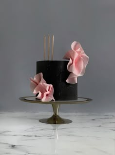 a black cake with pink flowers on top