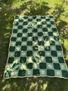 a green and white crocheted blanket laying on the grass